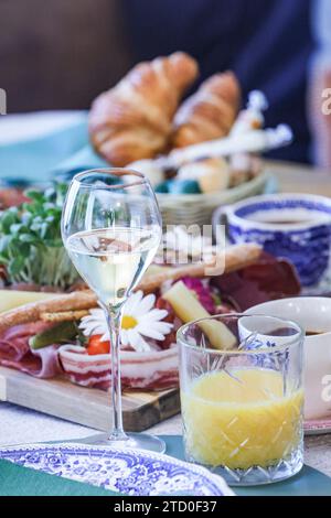 Elegant brunch setting with a glass of white wine, fresh croissant, and assorted delicacies. Stock Photo