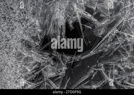 A close-up black and white photograph capturing the complex pattern of ice crystals with a dark void at the center. Stock Photo