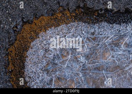 Intricate frost patterns forming a natural mosaic on the ground contrasted with a brown earthy edge. Stock Photo
