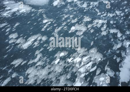 A high-resolution image capturing the intricate details of a frozen lake, speckled with patterns of snow and ice. Stock Photo