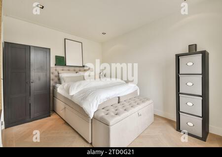 Wooden cabinet and wardrobe with bed and bench in spacious white bedroom of modern apartment Stock Photo