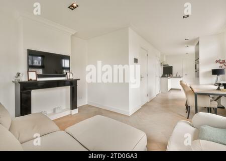 Television on mantelpiece by sofa in living room with view of kitchen counter in modern apartment Stock Photo