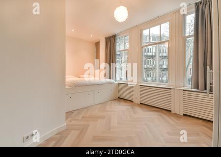 Large comfortable bed and parquet floor in spacious bedroom at modern apartment with pendant light and window Stock Photo