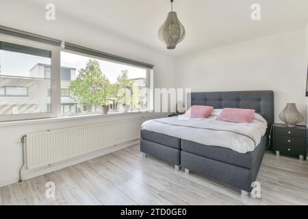 Pendant light hanging over comfortable bed by large window in spacious bedroom at luxurious apartment Stock Photo