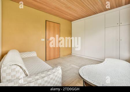 Comfortable couch located near wardrobe and table in spacious minimalist style living room in modern apartment Stock Photo