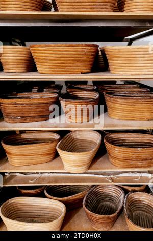 Various wooden brown proofing baskets for baking bread and pastry items arranged on shelves in kitchen at bakehouse Stock Photo