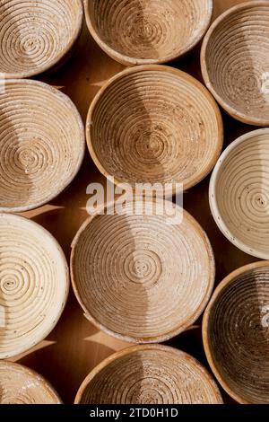 High angle view of brown wooden circular proofing baskets for baking bread arranged on table in kitchen at bakehouse Stock Photo