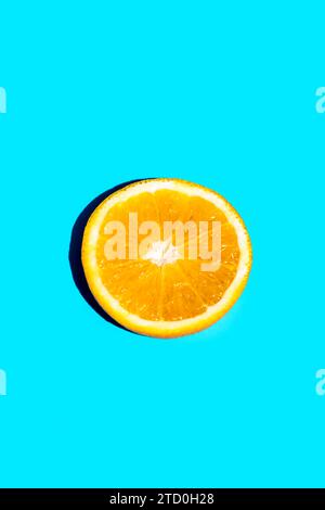 Closeup of slice of fresh orange fruit isolated on blue background with copy space Stock Photo