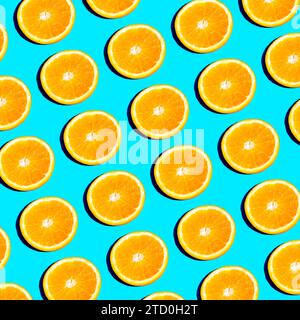 From above slices of vibrant orange citrus fruit arranged in a repetitive pattern on a bright blue background, creating a fresh and summery feel Stock Photo