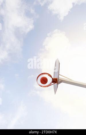 From below of basketball making basket against cloudy blue sky at court on sunny summer day Stock Photo