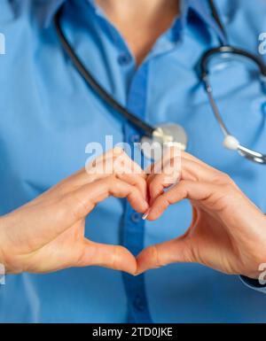 Cropped portrait of female doctor making a heart shape with hands. Health care Stock Photo