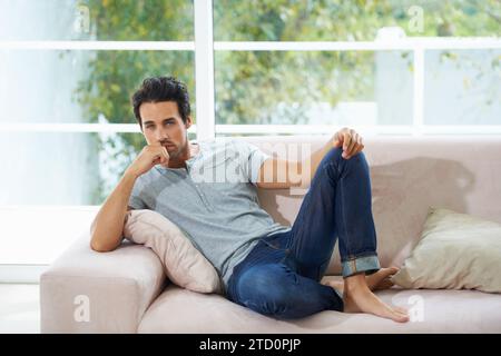 Man, portrait and sofa relax in home for weekend rest or holiday calm, chill on vacation morning. Male person, face and living room peace or thinking Stock Photo