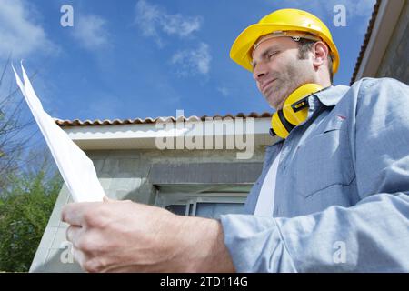 thoughtful constructor planning while looking at plan Stock Photo