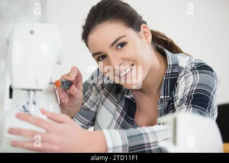 woman repairing sewing machine with a screwdriver Stock Photo