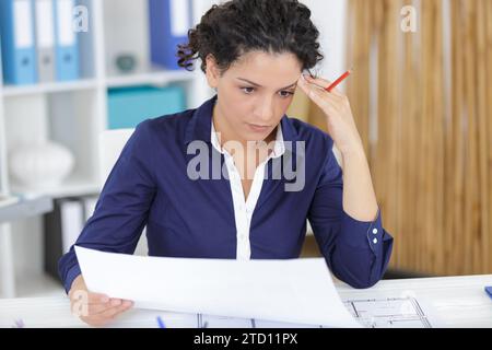 young woman architect constructor analyzing blueprint in office Stock Photo