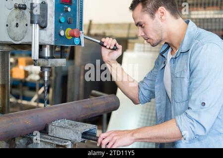 mature man using a drilling machine at industrial factory Stock Photo