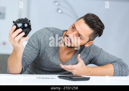 young confused man holding piggy bank Stock Photo