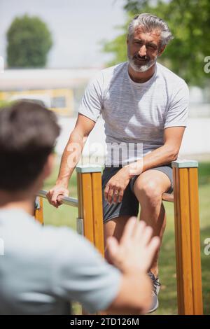 senior man and son doing pull-ups on horizontal bar Stock Photo