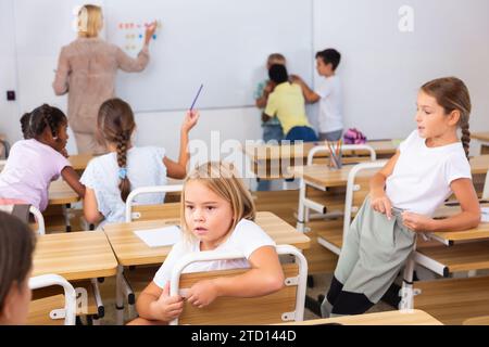 Tween boys and girls friendly talking in break in classroom Stock Photo