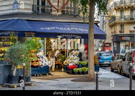 A woman with a bunch of flowers leaving Monceau Fleurs, a Paris florist shop on 8 Rue de Maubeuge in the 9th arrondissement of Paris, France Stock Photo