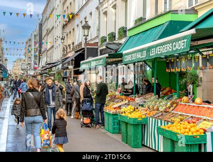 A young family out shopping in Paris walking past Les Vergers Cadet a fruit and vegetable shop on Rue Cadet in the 9th arrondissement of Paris,France Stock Photo