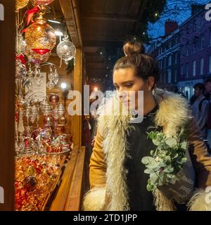Young woman wearing a warm Afgan coat looking at a stall at York St Nicholas Christmas Market 2023. UK Stock Photo