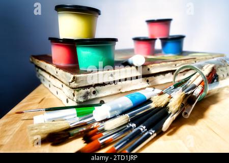 old canvases with a set of painting brushes and some tubes of oil paints lie on a wooden table Stock Photo