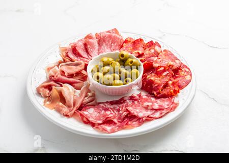 Assortment of Italian and Spanish sliced meat appetizer, prosciutto, salami and ham, with olives Stock Photo