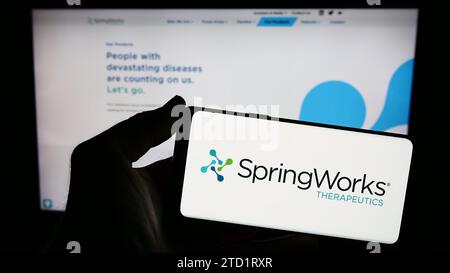Person holding smartphone with logo of American biotechnology company SpringWorks Therapeutics Inc. in front of web page. Focus on phone display. Stock Photo