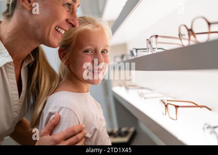Smiling woman and child looking at new eyeglasses in optical store Stock Photo