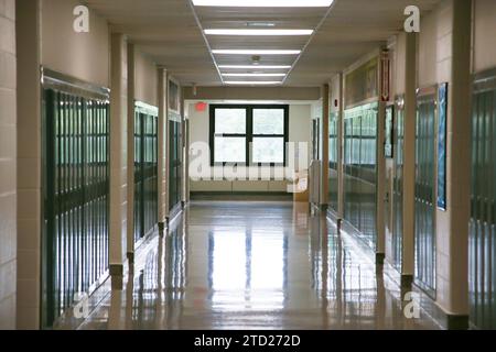 A long hallway lined with school lockers leading to a window in a high school building. Stock Photo