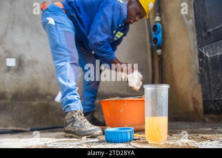 Young African blue collar worker washing the filters' containers. Water filtration concept. Stock Photo