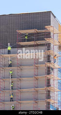 Unrecognizable workers removing timber planks from scaffolding at a building construction site in Salt Lake City, Utah, USA Stock Photo