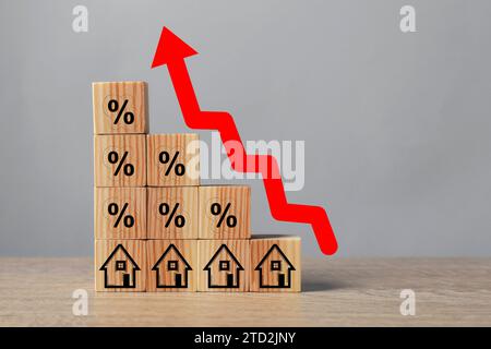 Mortgage rate rising illustrated by upward arrow over cubes with percent signs and house icons on wooden table Stock Photo