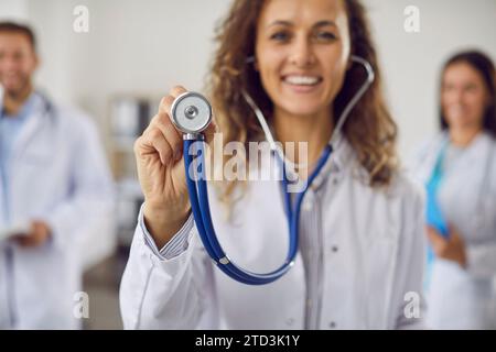 Portrait of a young happy smiling doctor in medical uniform standing with stethoscope in clinic. Stock Photo