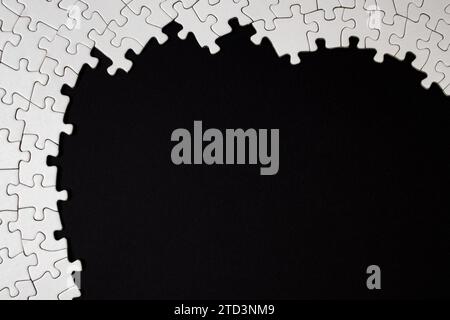 Plain white jigsaw puzzle frame on black color background Stock Photo