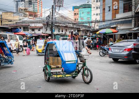 A tuk tuk or trike driver makes his way through the busy streets of the Binondo district of Manila, The Philippines. Stock Photo