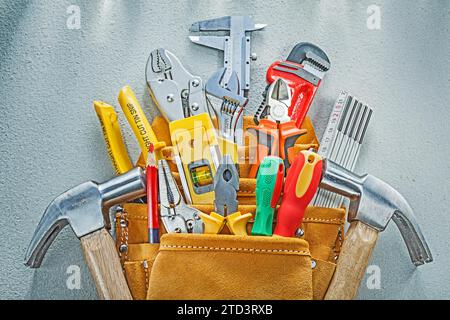 Composition of construction tooling in tool belt on concrete background Stock Photo