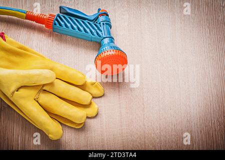 Set of leather gloves garden rubber hose water sprinkler on wood board gardening concept Stock Photo