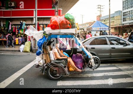 A tuk tuk or trike laden with shopping goods makes its way through the busy streets of Manila. Stock Photo