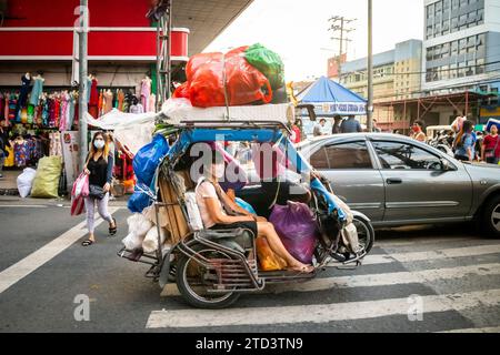 A tuk tuk or trike laden with shopping goods makes its way through the busy streets of Manila. Stock Photo