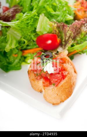 Original Italian fresh bruschetta, typical finger food, with fresh salad and vegetables on background, MORE DELICIOUS FOOD ON PORTFOLIO, food Stock Photo