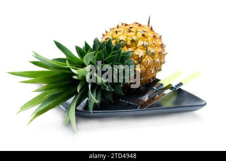 Pineapple on a black plate with knife and fork isolated on white background, food photography Stock Photo