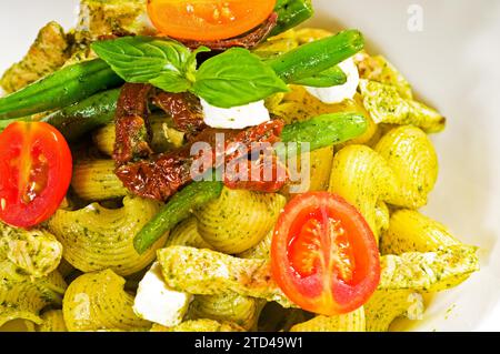 Fresh lumaconi pasta and pesto sauce with vegetables and sundried tomatoes, tipycal italian food, food photography Stock Photo
