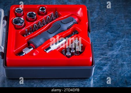 Opened toolbox with screwdriver and interchangeable bits and heads on a scratched metal background Design concept Stock Photo