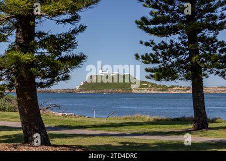Nobbys Lighthouse, Nobbys Head, on the entrance to Newcastle Harbour, Newcastle, New South Wales, Australia. Seen from the distance, framed by trees. Stock Photo