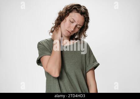 Tired upset woman suffering from fatigued massaging hurt stiff neck rubbing tensed muscles to relieve joint pain. Symptom of cervical chondrosis. Inflammation of vertebra, fibromyalgia concept Stock Photo