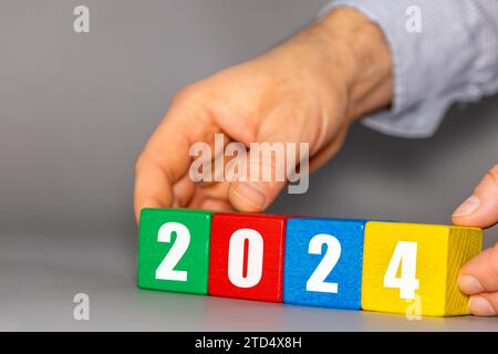 year 2024, New year symbol on colorful wooden cubes arranged by businessman, Concept New 2024 year, trends, planning, business Stock Photo