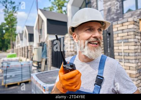 Joyful construction foreman using two-way radio on site Stock Photo