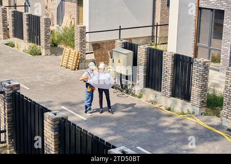 Team of construction professionals examining blueprints on site Stock Photo